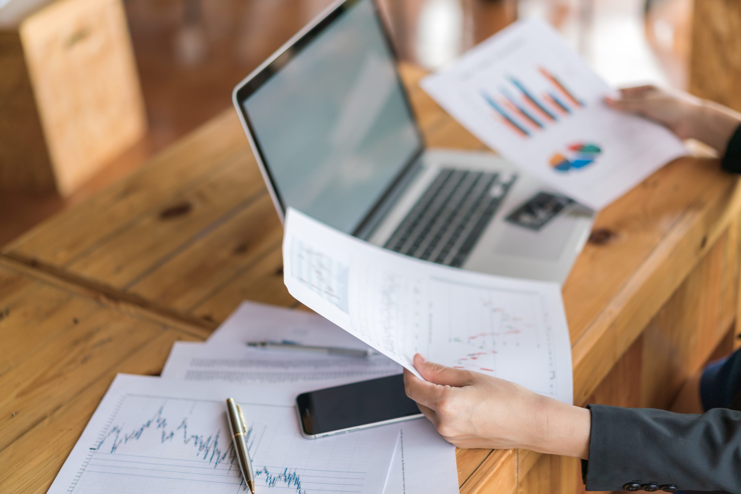 Business woman hand with Financial charts and laptop on the tabl